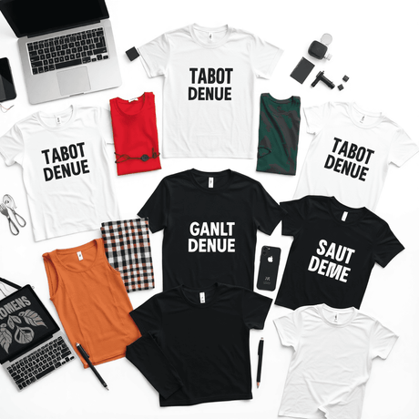 Flat lay of T-shirt mockups with various designs, a laptop, and design tools on a clean surface, highlighting professional clothing brand design.