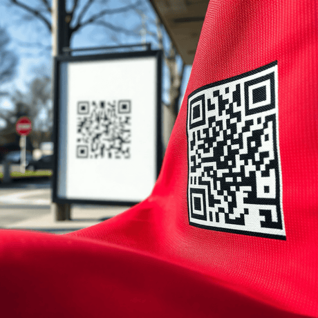 Close-up of a black and white QR code on vibrant fabric, with soft light highlighting texture and a blurred outdoor QR code sign in the background.